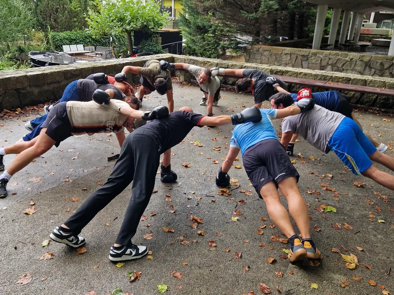 Collega's doen samen een plank in een cirkel tijdens een bedrijfsbootcamp buiten