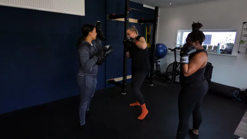 Drie vrouwen trainen kickboksen met pads in de zaal van Convert2Fit