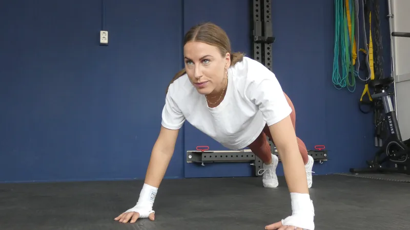 Vrouw in plankpositie kijkt in de camera tijdens een training bij Convert2Fit in Amsterdam Nieuw-West